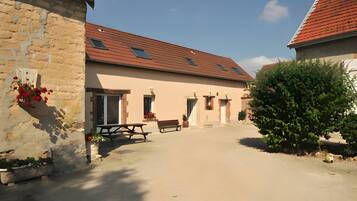 A courtyard with a building featuring a tiled roof and a bench.