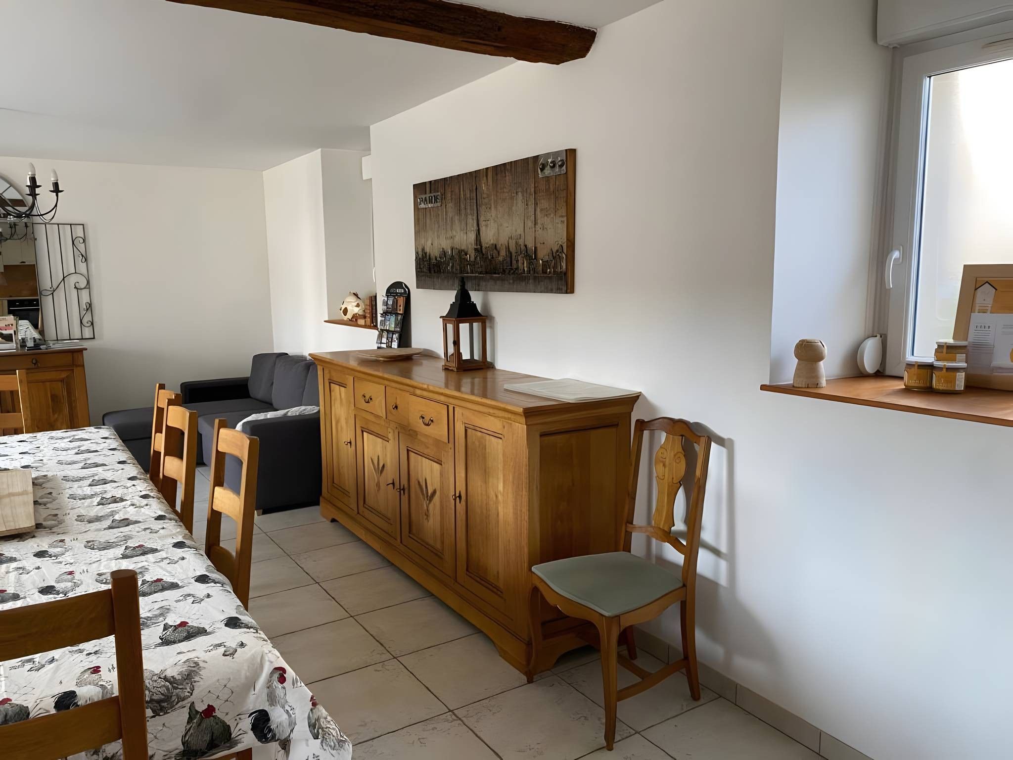 A dining area with a table, chairs, a wooden cabinet, and a painting on the wall.