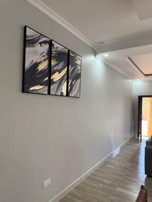 A hallway with a modern light fixture, a wall-mounted artwork, and a door leading to another room. - Cozy 2-bedroom apartment in brilliant Lusaka with AC (Lusaka)