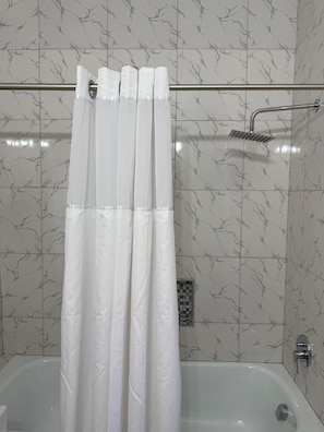 Un baño con cortina de ducha, bañera y cabezal de ducha.
