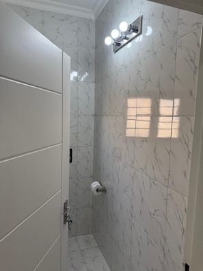 Un baño con zona de ducha, inodoro y perchero para toallas.