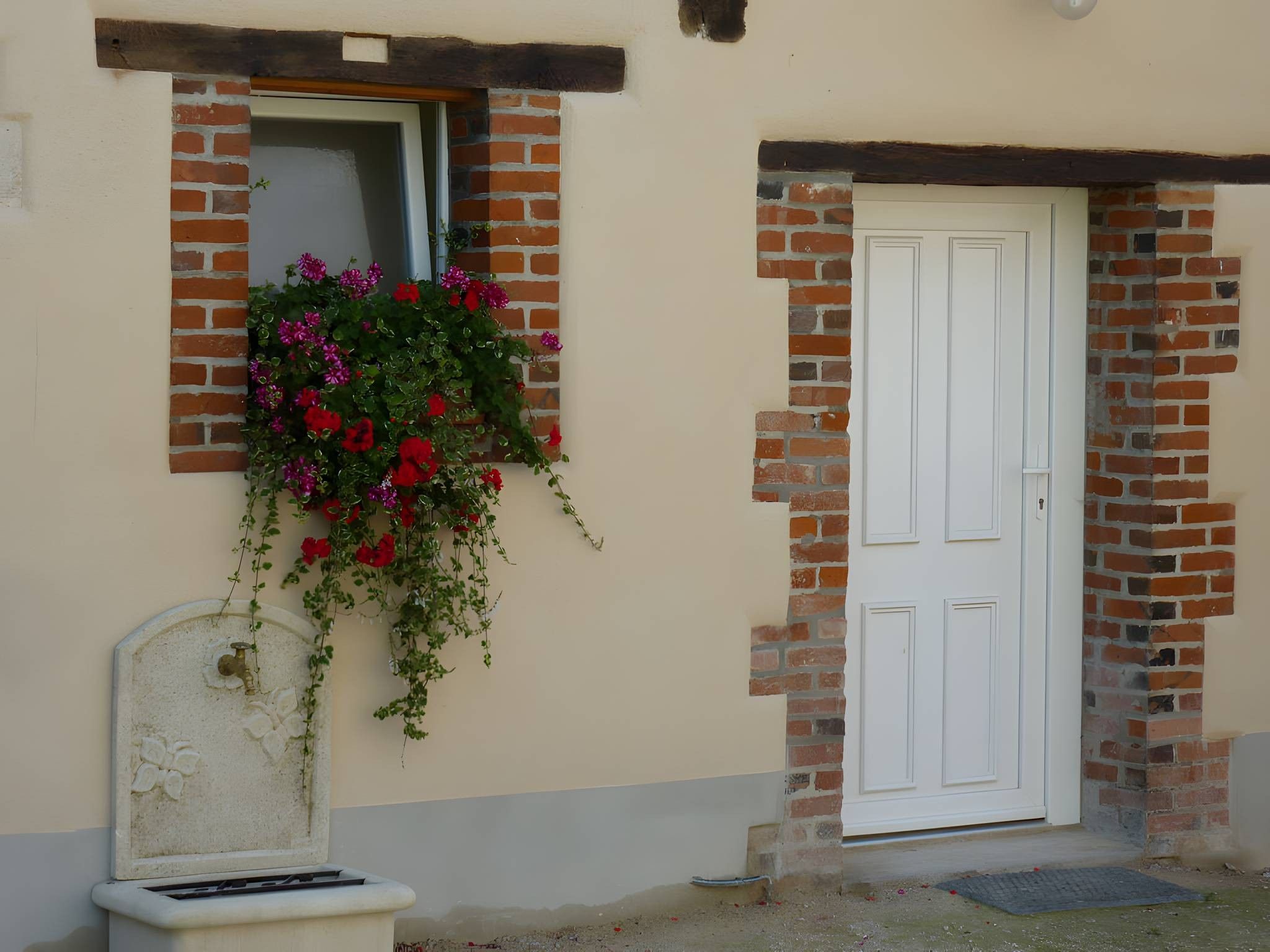 A building with a white door and a window with hanging flowers.