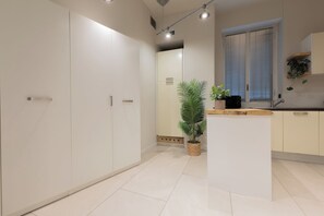 A modern kitchen with white cabinetry, a central island, and a potted plant. - Flatsharing - Nava Suites (Milan)