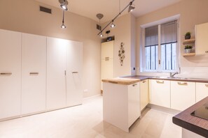 A modern kitchen with white cabinetry, a wooden countertop, and a window with blinds. - Flatsharing - Nava Suites (Milan)