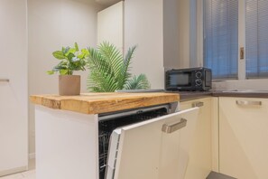 A kitchen with a microwave, a wooden cutting board, and a potted plant. - Flatsharing - Nava Suites (Milan)