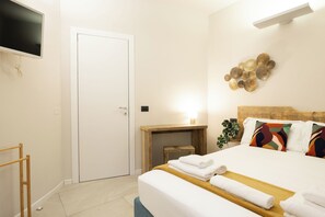 A hotel room with a bed, a desk, a TV, and a door. - Flatsharing - Nava Suites (Milan)