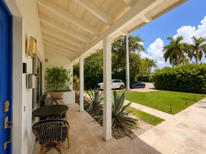 A covered outdoor seating area with a table and chairs, a door, and a view of a lawn and parked cars. - ★★★★★4BD/3BA VILLA.CLOSE TO THE OCEAN.HEATED POOL! (Hollywood)