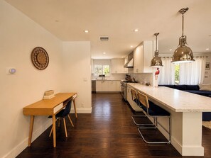 Een moderne keuken met een centraal eiland, een houten eettafel en barstoelen.