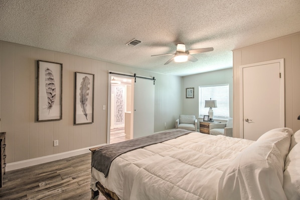 A bedroom with a bed, a ceiling fan, and two framed feathers on the wall.
