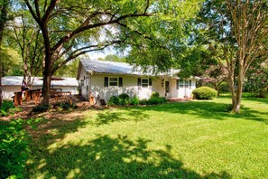 A single-story house with a front porch, surrounded by a well-maintained lawn and trees.