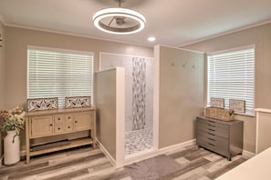A bathroom with a shower, vanity, and a ceiling light fixture.