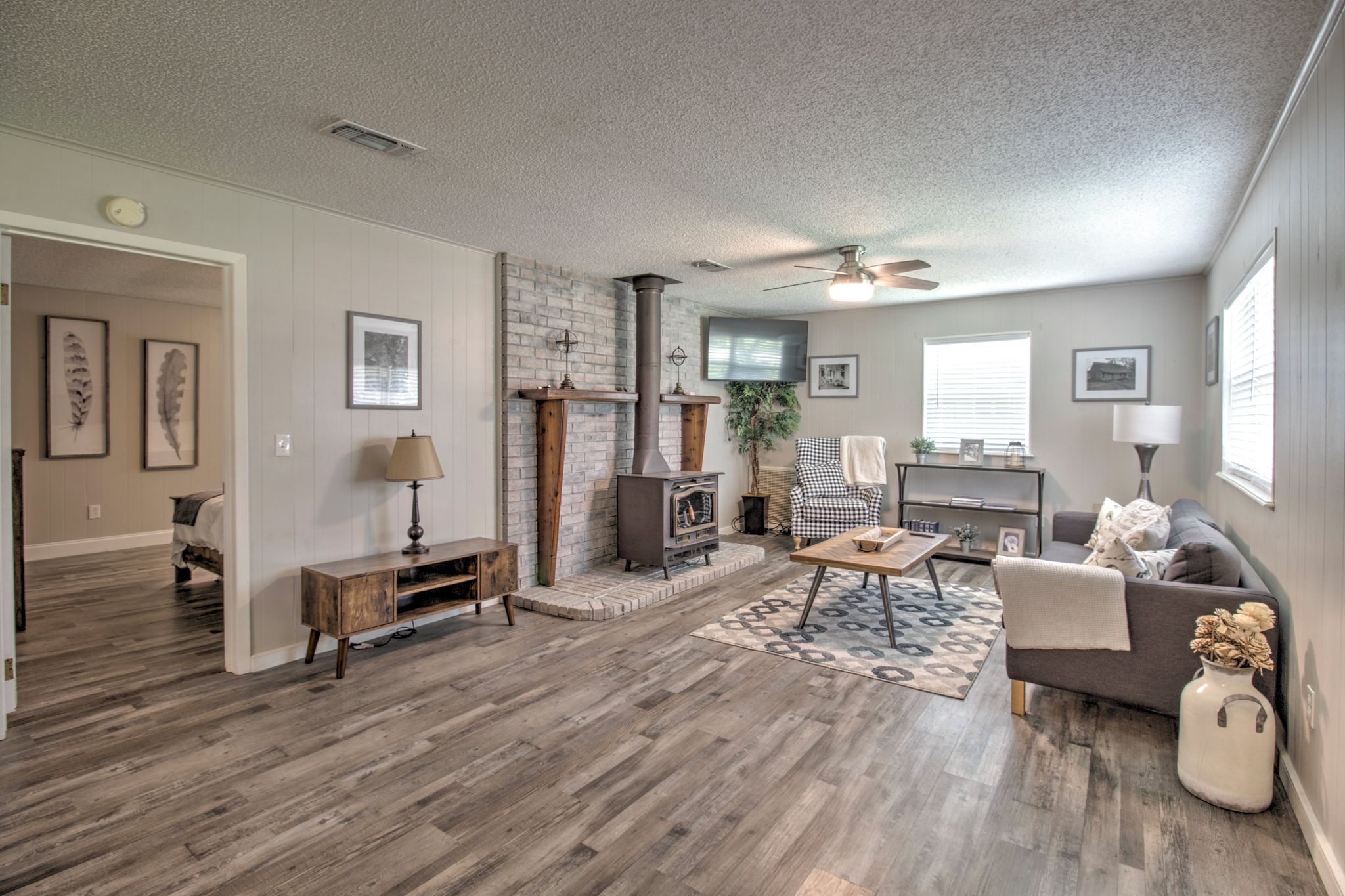 A spacious living room with hardwood flooring, a fireplace, a sofa, a coffee table, and a ceiling fan.