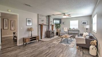 A spacious living room with hardwood flooring, a fireplace, a sofa, a coffee table, and a ceiling fan.