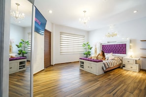 A modern bedroom with a large bed, a vanity, and a television.
