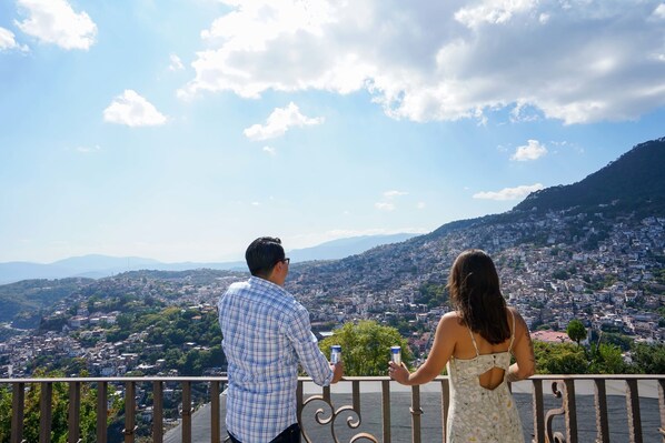 A couple overlooking a cityscape from a balcony with a railing.