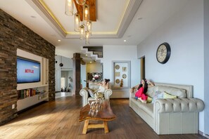 A modern living room with a flat-screen TV, a wooden coffee table, a beige sofa, and a staircase leading to another level.