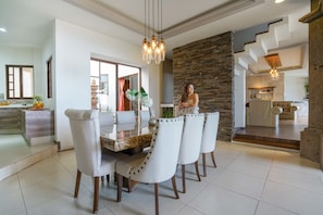A modern dining area with a marble table, white upholstered chairs, and a stone accent wall.