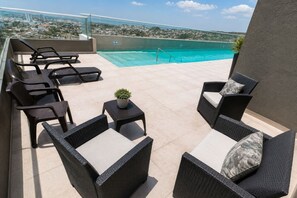 A rooftop terrace with a pool, lounge chairs, and a view of the city. - Sunlit Haze | 3BR,Beach, Sea View & Pool (Cartagena)