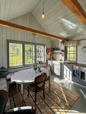 A kitchen with wooden cabinets, a dining table, and a built-in oven. - Lakeside cabin at Älmtasjön with sauna & hot tub (Asarum)