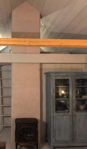 Ein Zimmer mit Holzboden, einem Schrank mit Glastüren und einem kleinen Tisch.