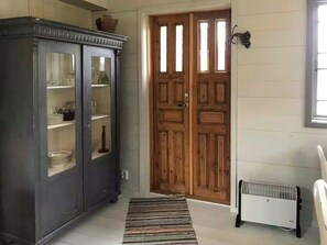 Ein Zimmer mit einem dunklen Holzschrank, einer doppelten Holztür, einem Heizkörper und einem Streifen Teppich.