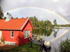 A red house by a calm lake with a rainbow. - Lakeside cabin at Älmtasjön with sauna & hot tub (Asarum)
