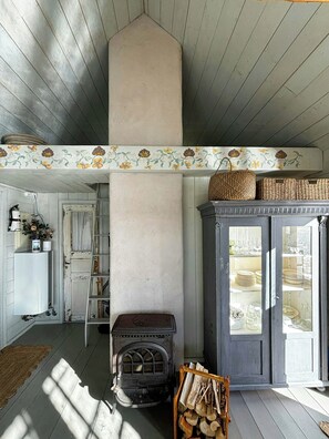 Ein rustikales Interieur mit Kamin, Holzbalken und einer dekorativen Blumenbordüre.
