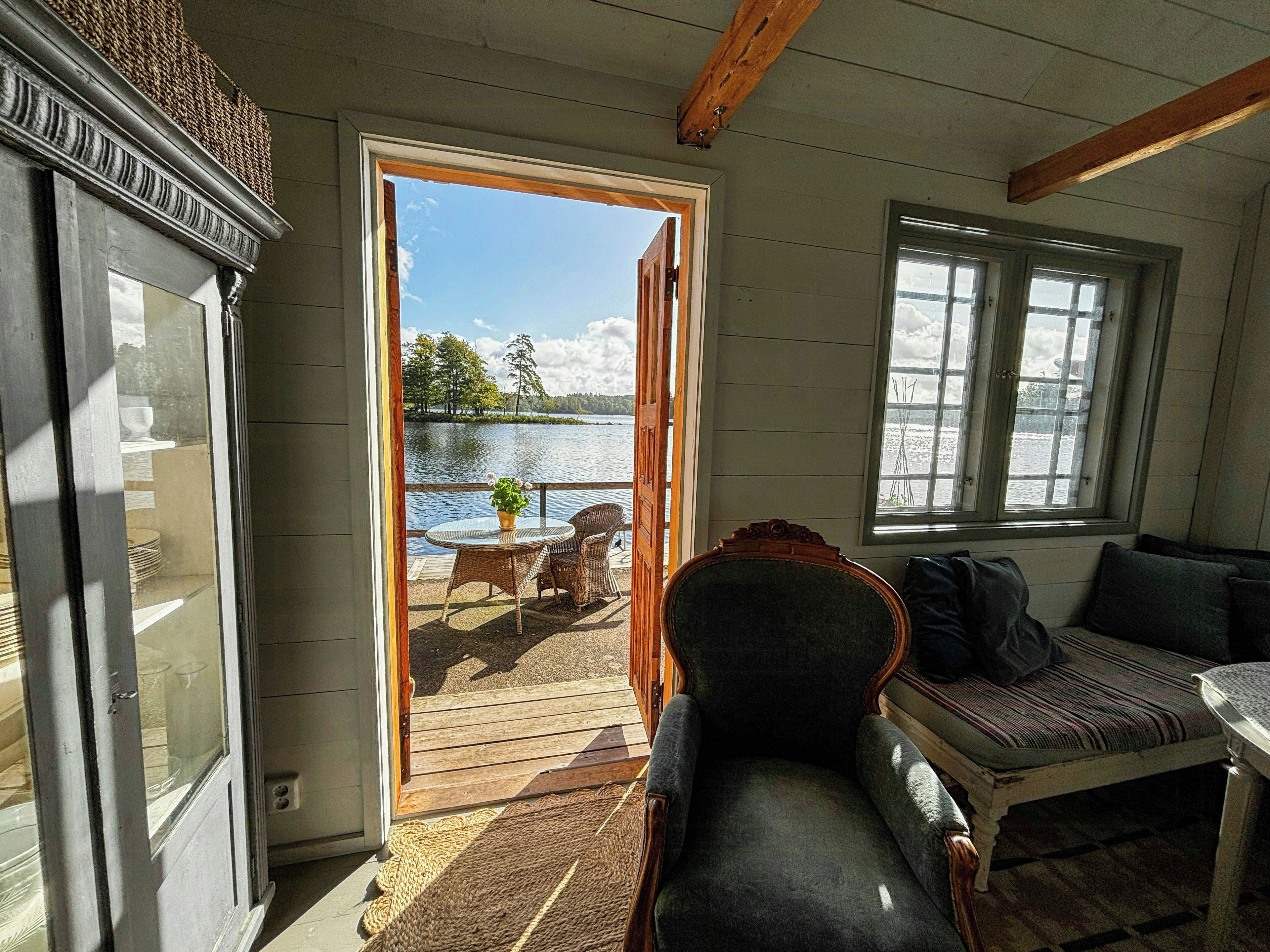 Une pièce avec vue sur un lac, une table à manger avec des chaises, un canapé et une fenêtre.