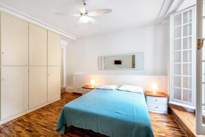 Ein Schlafzimmer mit Bett, Nachttischen, Deckenventilator, Kleiderschrank und einem Fenster mit Blick.
