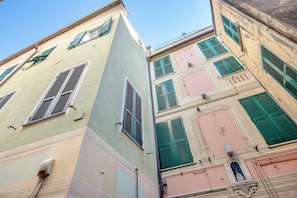 Ein mehrstöckiges Gebäude mit traditioneller Architektur, das mehrere Fenster mit Fensterläden, eine sichtbare Tür und einen kleinen Balkon aufweist.