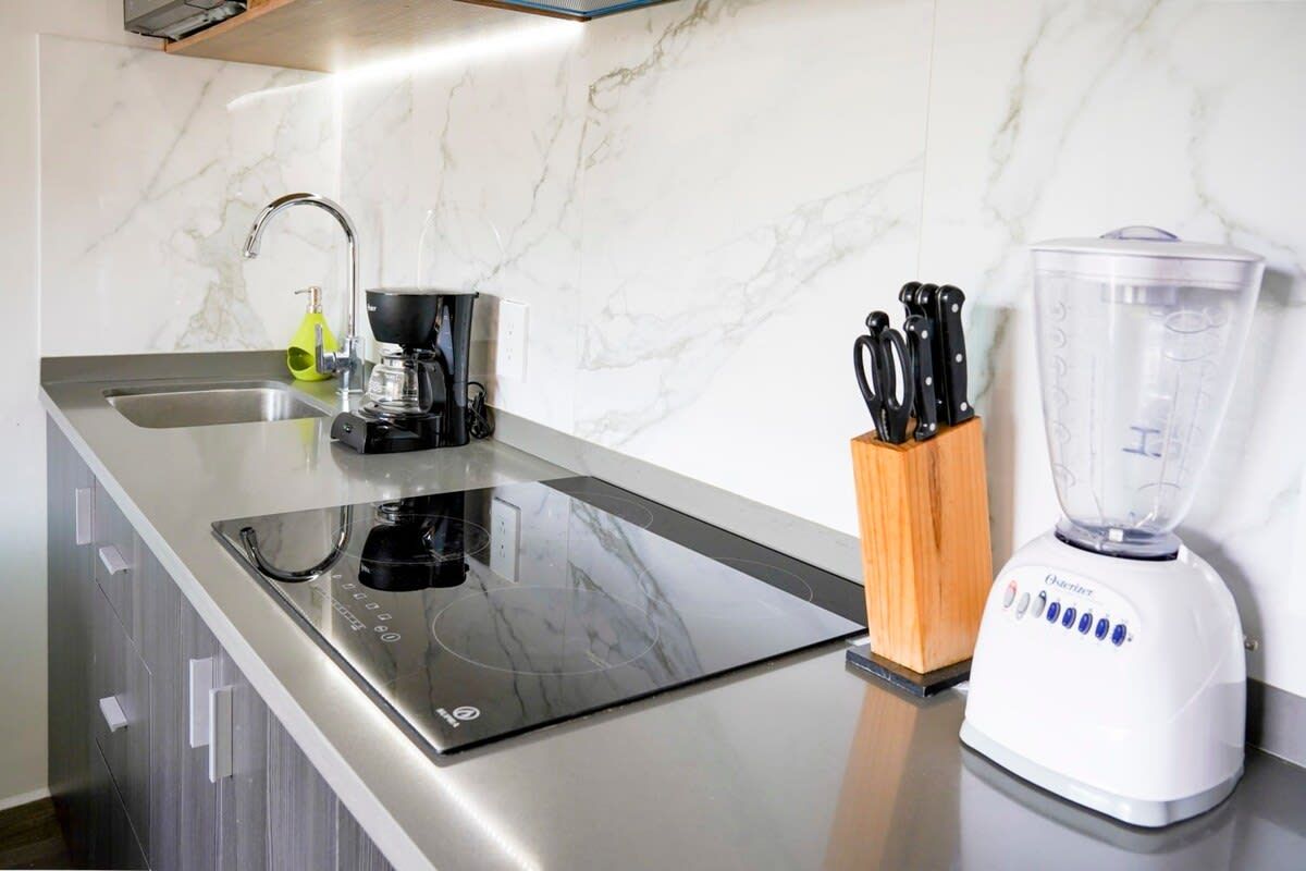 Een keuken met een inbouw inductiekookplaat, een spoelbak en een blender op het aanrecht.
