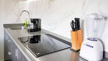 Een keuken met een inbouw inductiekookplaat, een spoelbak en een blender op het aanrecht.