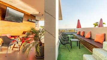A rooftop terrace with seating, a TV, and a view of the city.