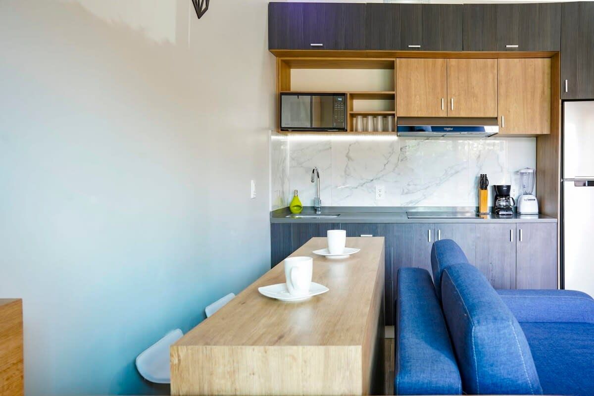 A modern kitchen with a wooden dining table, a built-in microwave, and a coffee machine.