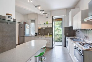 Eine moderne Küche mit einer großen Kochinsel, eingebauten Geräten und Blick ins Freie.