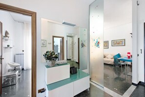 Ein modernes Wohnzimmer mit einem Glastisch, einer Couch und einem Essbereich mit einer roten Lampe.