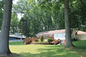 A residential property with a wooden deck, a brick house, and a white fence. - Lake House with HUGE Beach Front (Grand Junction)