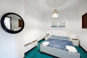 Ein Schlafzimmer mit einem Bett, Nachttischen, einem Spiegel und Kunstwerken an der Wand.