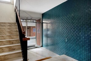 Eine Treppe führt zu einem Raum mit einer gemusterten Wand und einer Tür nach draußen.
