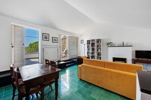 Una sala de estar con comedor, un sofá, un televisor y una estantería.