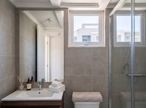 A modern bathroom with a large mirror, a sink, a glass shower enclosure, and a window. - Edificio Sucre Ñuñoa by Domus Travels (Ñuñoa)