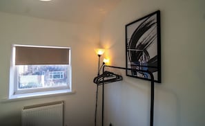 A room with a radiator, a window with a blind, a floor lamp, and a framed abstract painting on the wall. - Cosy & Stylish Home in St Helens (Saint Helens)