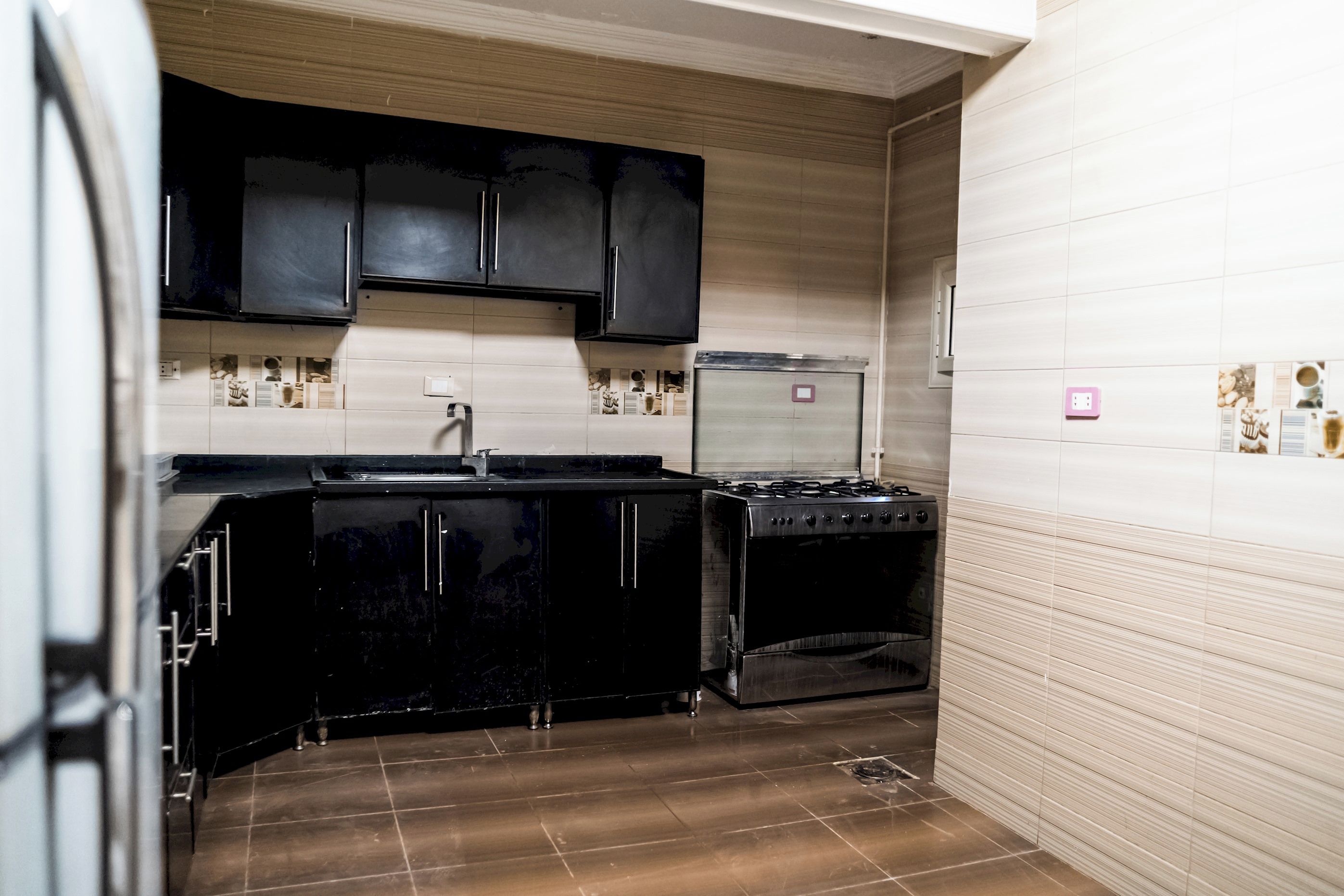 A compact kitchen with black cabinets, a stove, and a refrigerator.