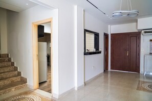 A modern interior with a staircase, a kitchen area, and a hallway leading to a door. - Single Room with Private Bathroom (Sheikh Zayed City)