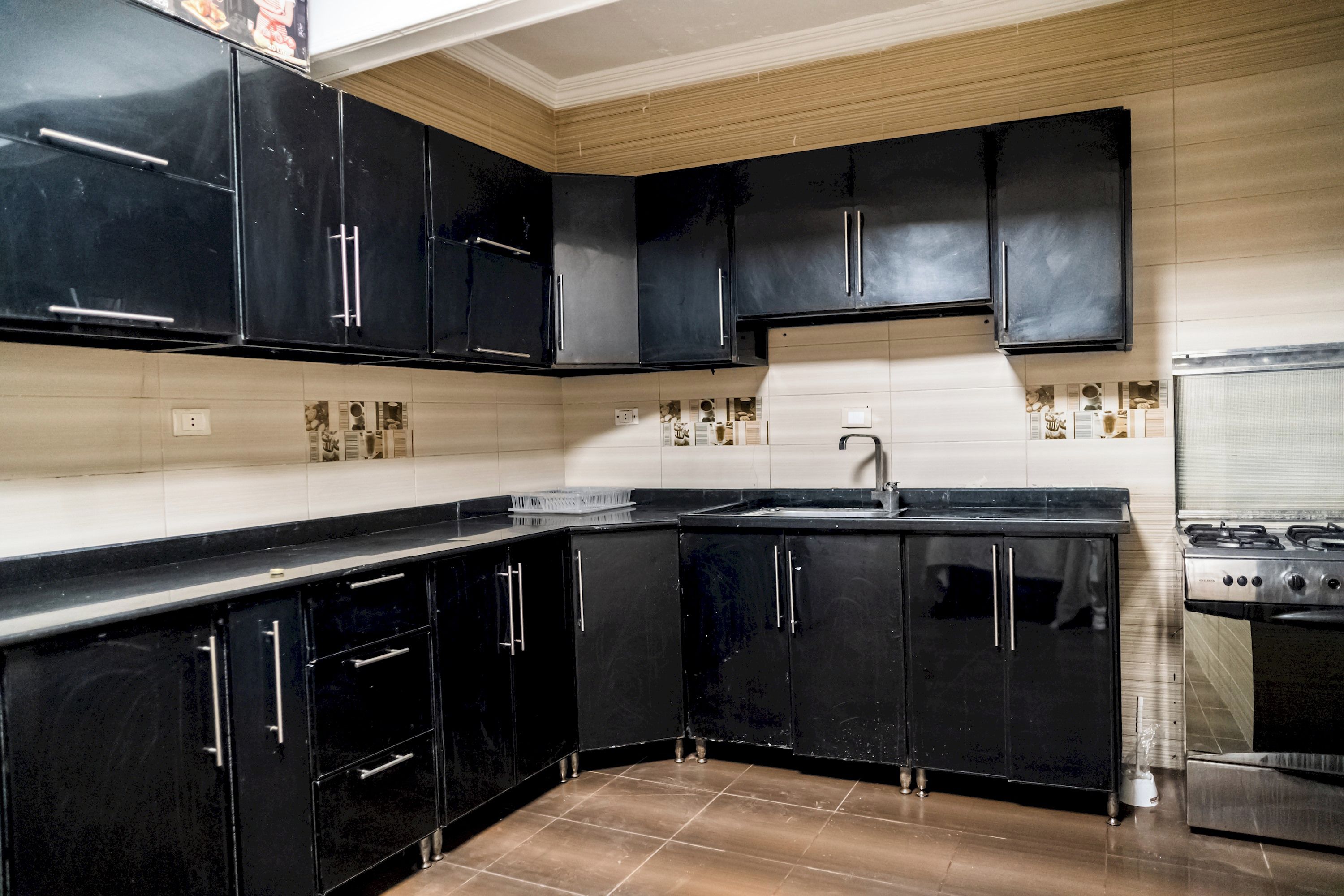 Una cocina con armarios negros, un lavamanos de acero inoxidable y una estufa.