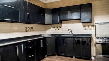 Una cocina con armarios negros, un lavamanos de acero inoxidable y una estufa.
