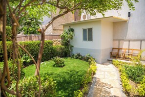 A residential garden with a pathway, a small building, and a wooden bench. - Deluxe Twin Room with Panoramic View (Sheikh Zayed City)