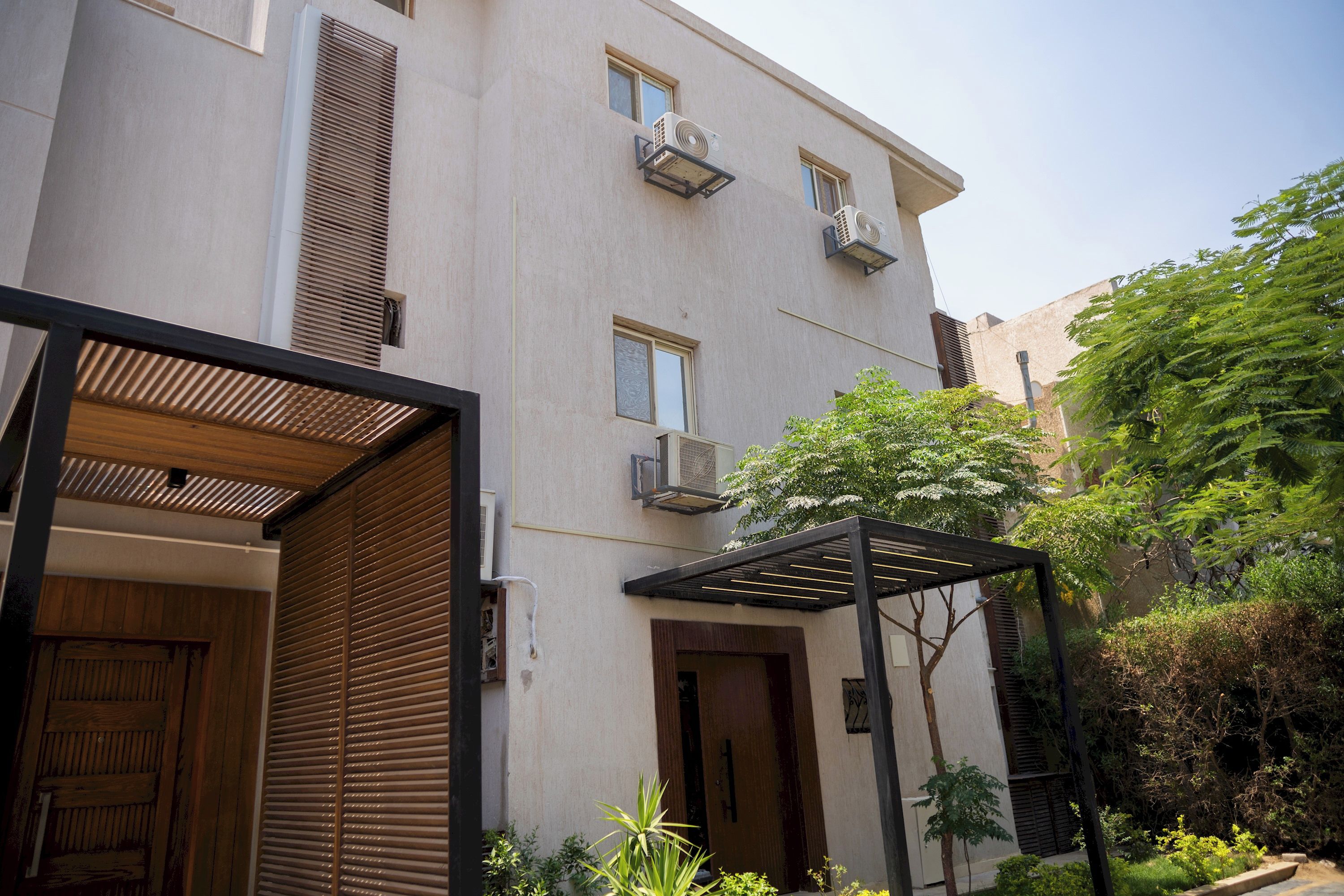 Un edificio moderno con fachada plana, varias ventanas y un equipo de aire acondicionado en la pared exterior.