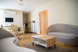 A modern living room with a sofa, a chair, a small table, and a TV mounted on the wall.