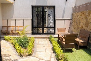 A patio with a stone pathway, a black gate, wicker furniture, and a small garden. - Deluxe Twin Room with Panoramic View (Sheikh Zayed City)